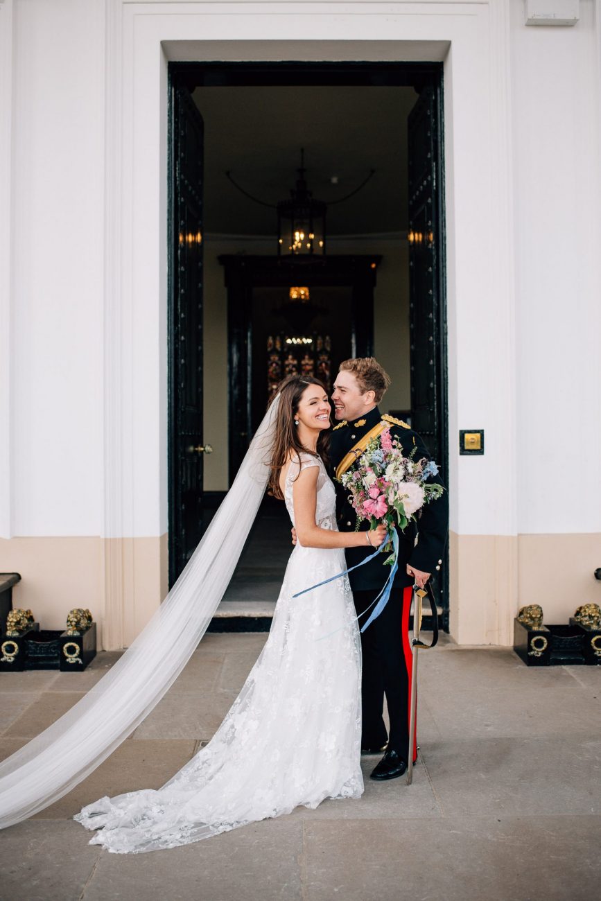 bride and groom laughing and hugging outside of sandhurst military academy