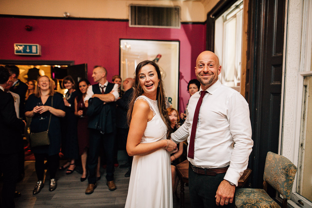 bride and groom smiling at camera in pub