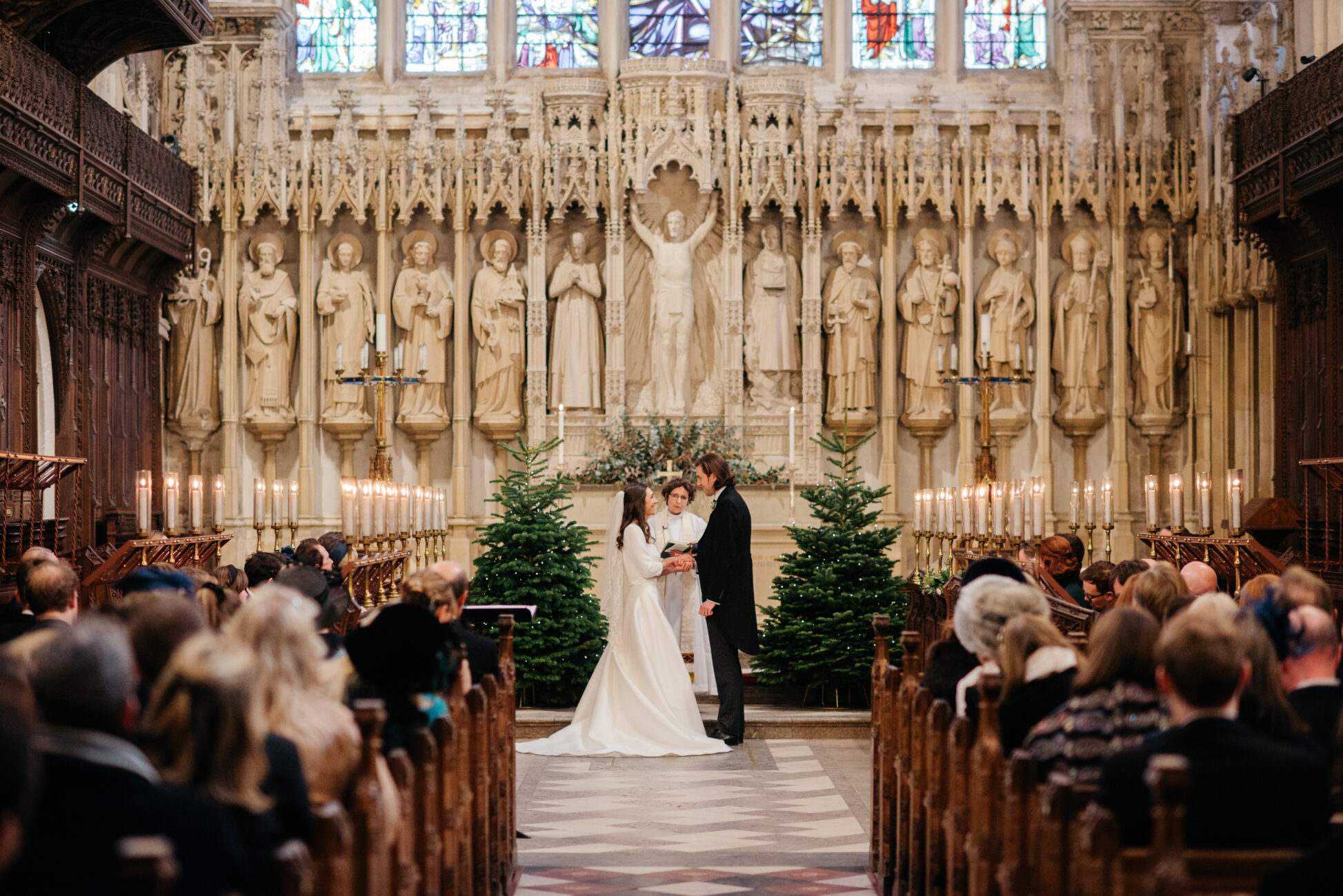 Bride and groom framed by Christmas trees Christmas wedding in Winchester Cathedral